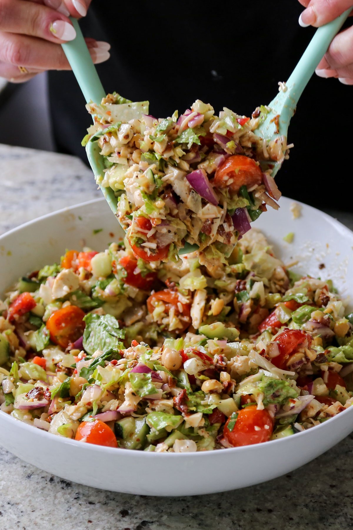 tossing the chopped Italian salad together with the dressing