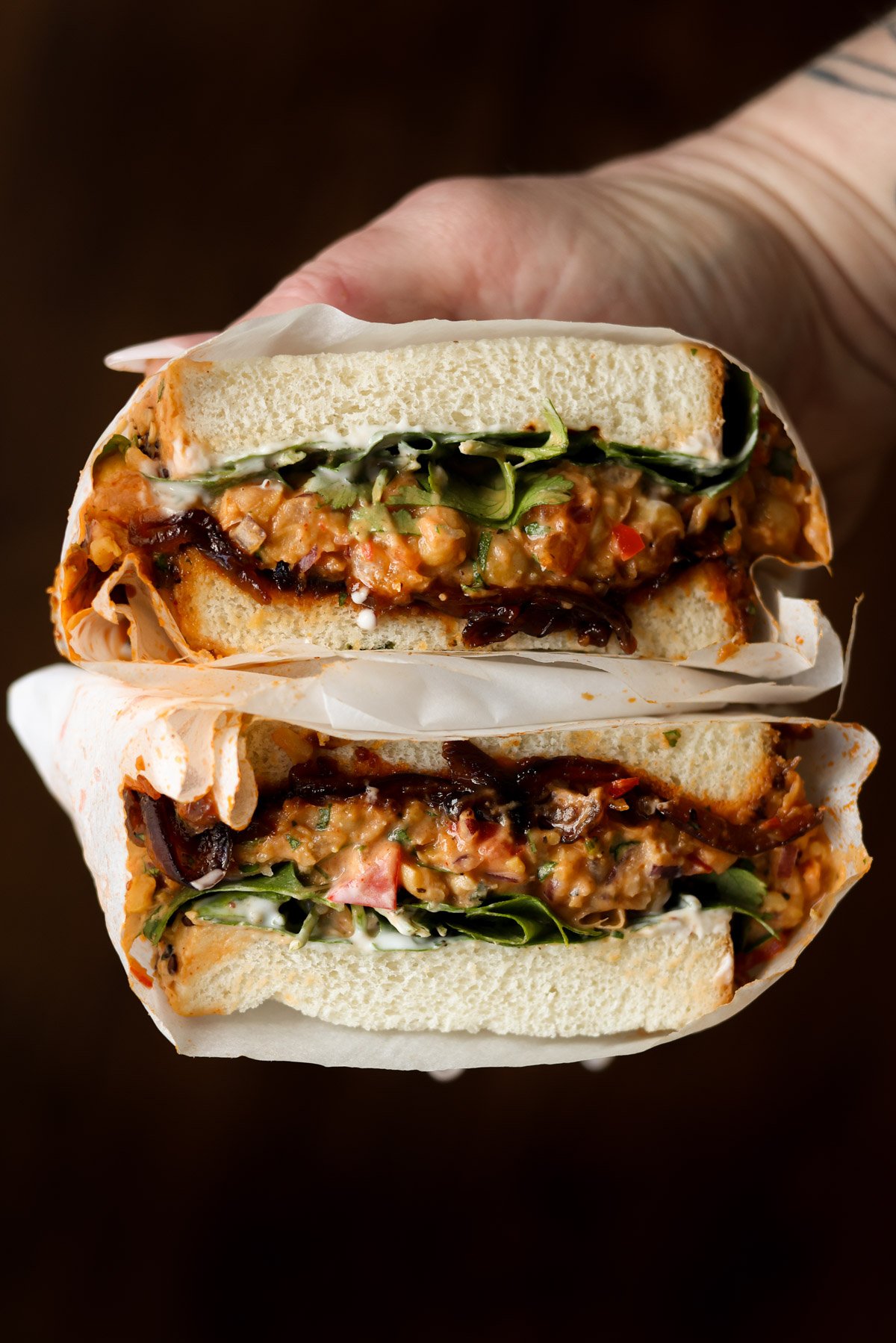 hand holding a gochujang chickpea salad sandwich