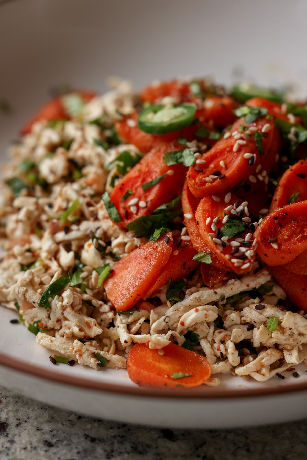 close-up of shredded tofu topped with roasted carrots in a bowl