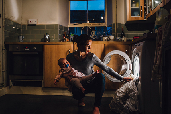 mom doing laundry while holding child