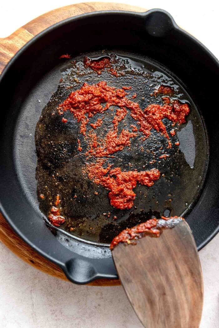 Taco seasoning and tomato paste cooking in a cast iron skillet.