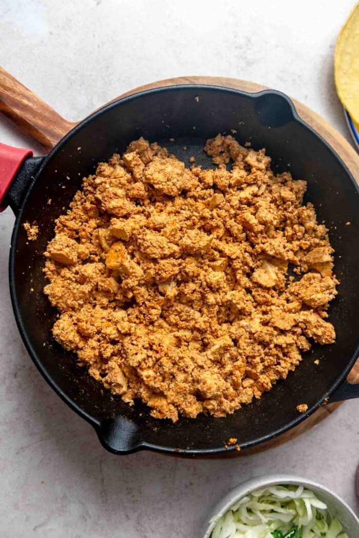 Seasoned tofu crumbles in a cast iron skillet.