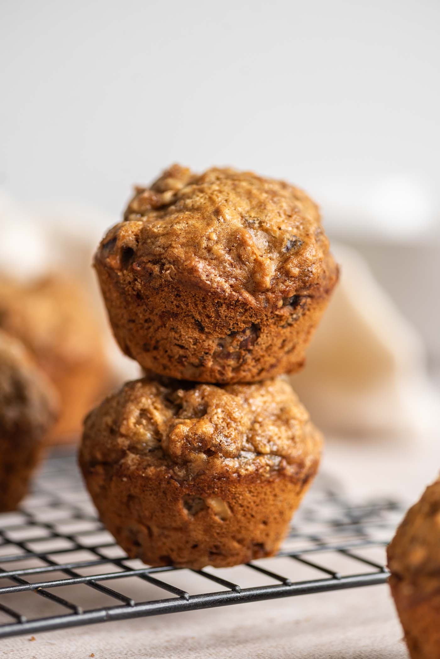 Two banana walnut muffins stacked on top of each other on a wire rack.