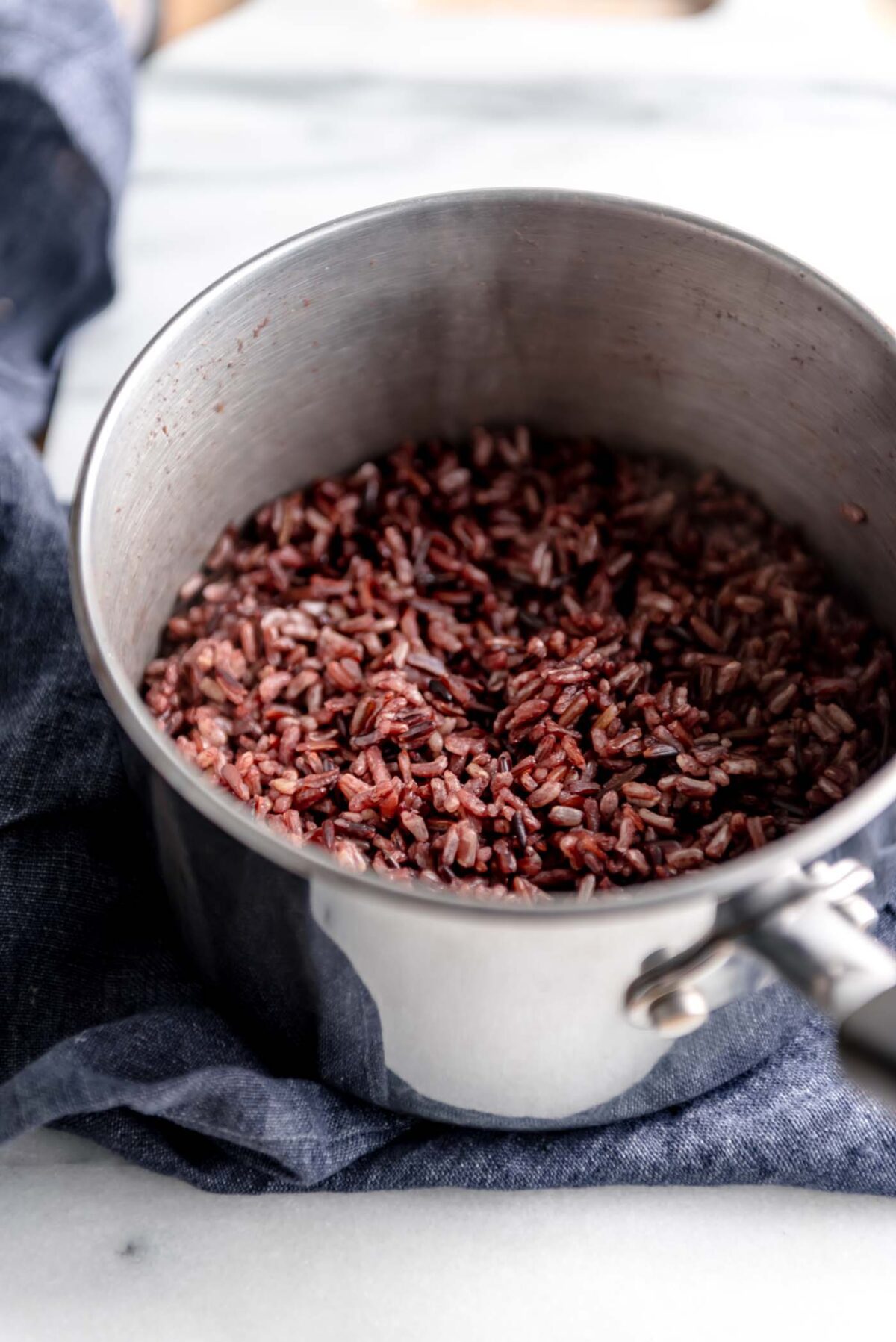 Cooked wild rice in a pot on a marble cutting board.