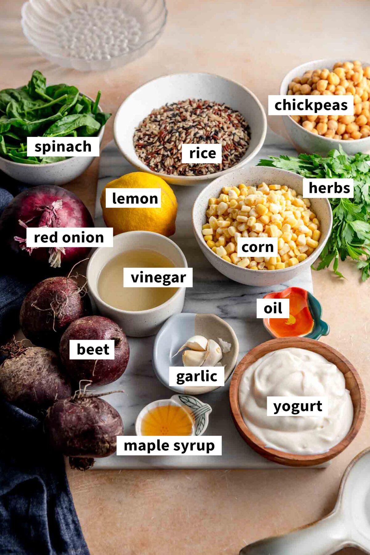 All the ingredients gathered in various bowls on a cutting board for making a wild rice bowl with chickpeas, corn, yogurt dressing and spinach.