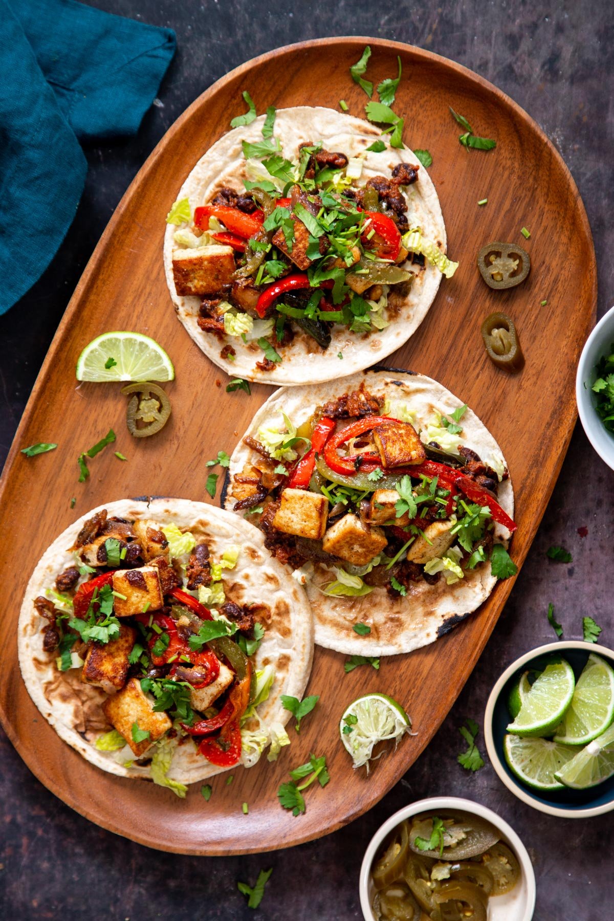 overhead shot of three small tacos with tofu and bell pepper filling topped with fresh cilantro