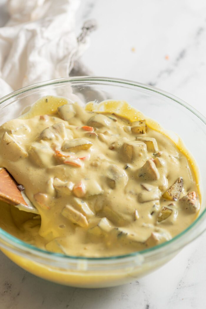 A thick omelette and vegetable batter in a glass mixing bowl.