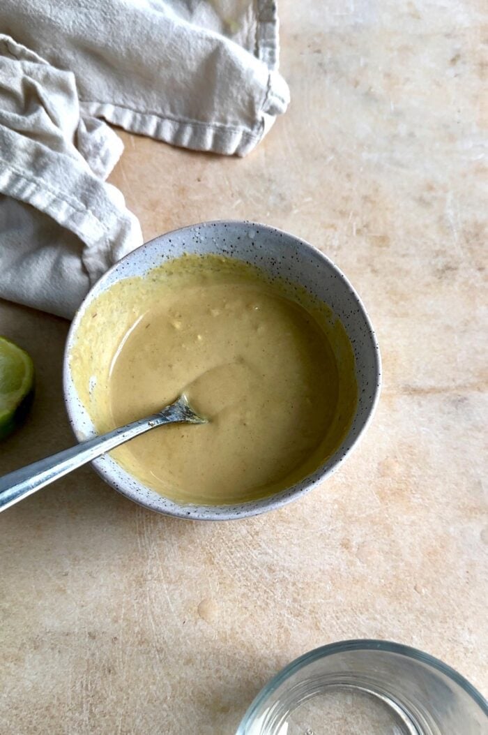 Creamy sauce in a small bowl with a spoon in it.