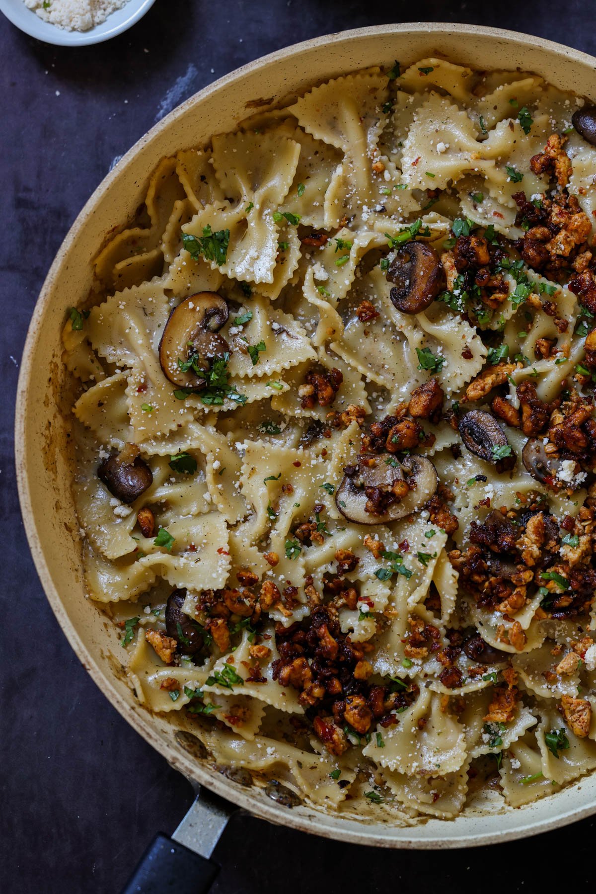 chili miso pasta in a bowl after topping with mushrooms and tofu crumbles