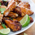 Crispy smoked chicken wings with lime wedges