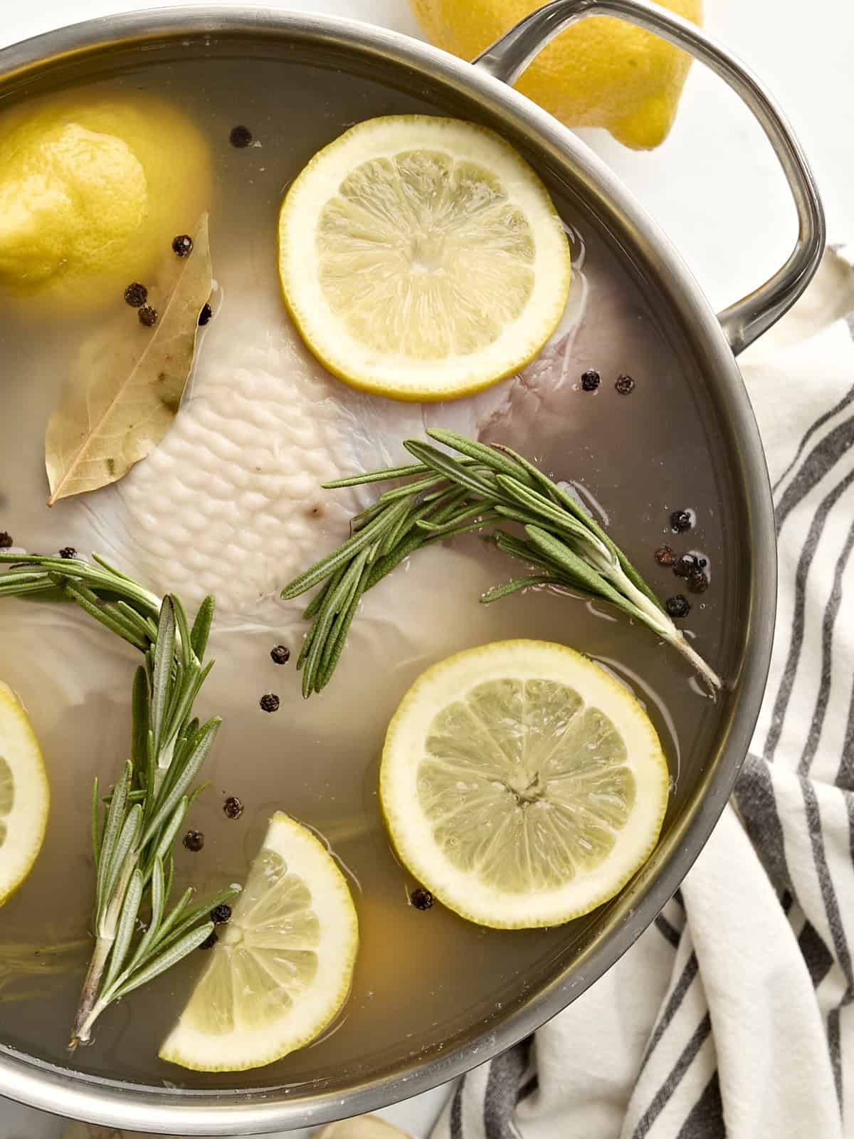 Overhead view of a turkey breast in a brine inside a large pot.