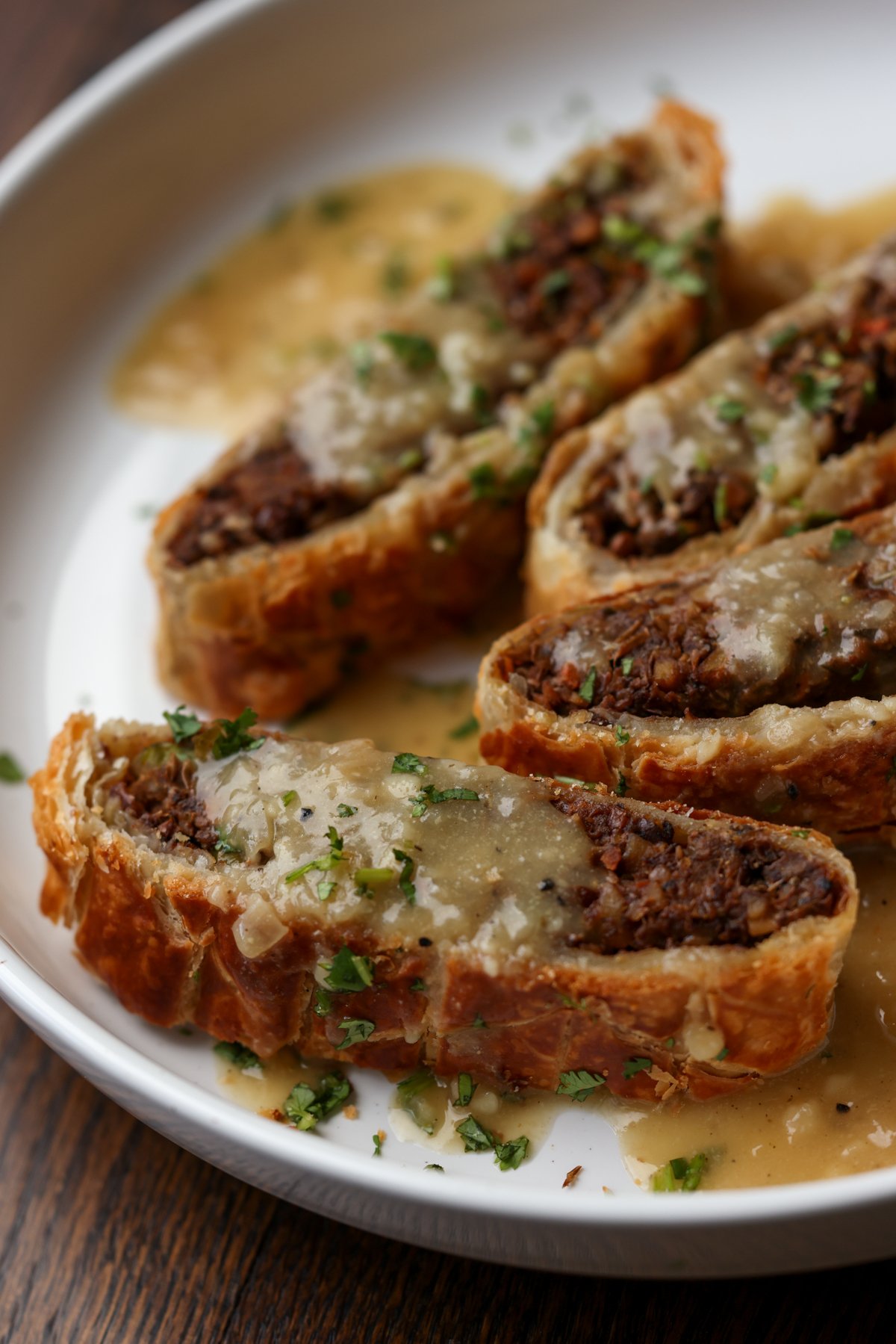 angled shot of lentil wellington on a plate with gravy to show more texture