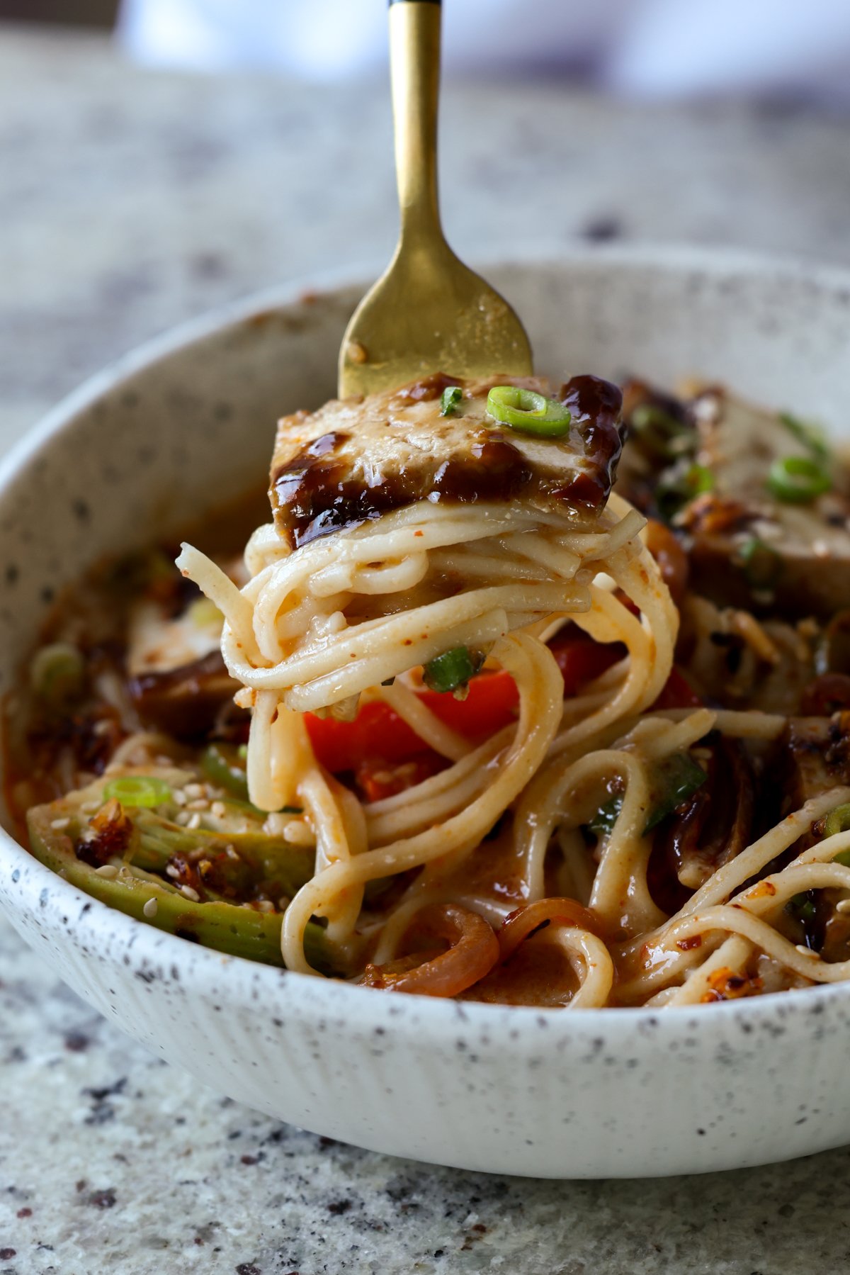 fork with a big bite of ramen noodles and tofu on it