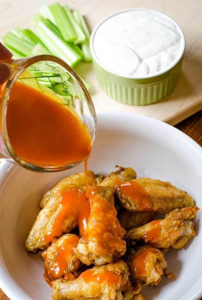 Hot sauce pouring over chicken wings