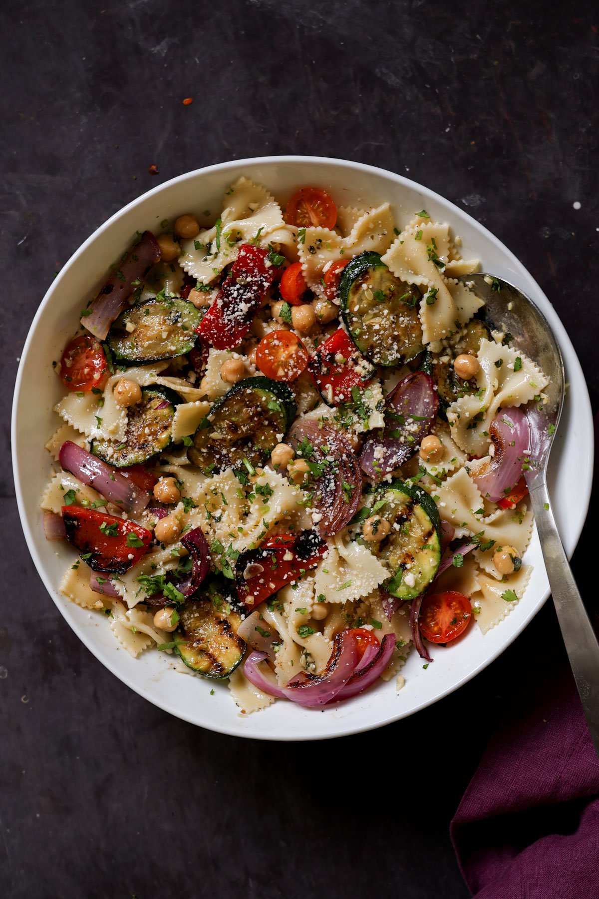 serving bowl of summer pasta salad with grilled vegetables with a spoon in it