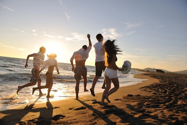 Friends running and having fun at the beach during sunset.