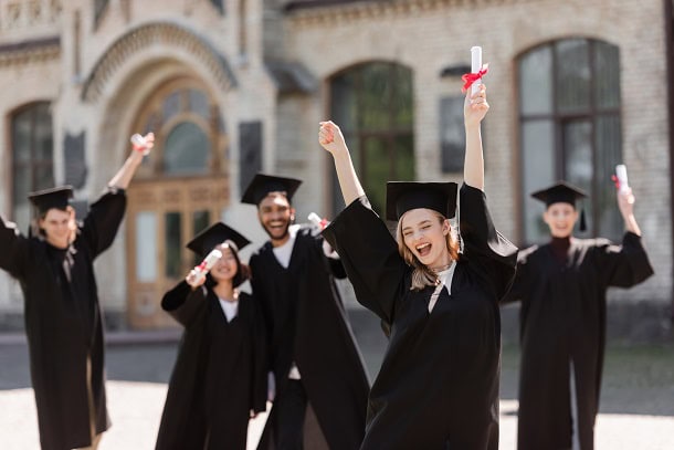 Happy students on graduation day celebrating outside their school.
